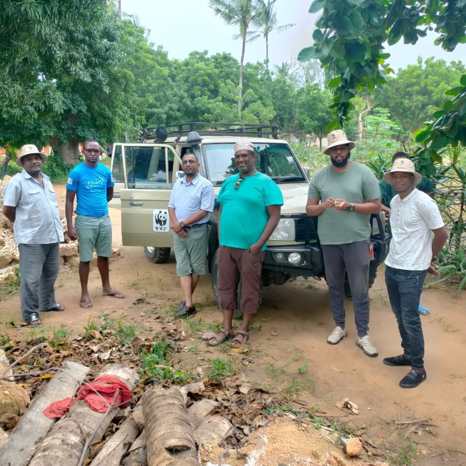 Team members and visitors standing near a pickup truck at Bwagabei Farms.